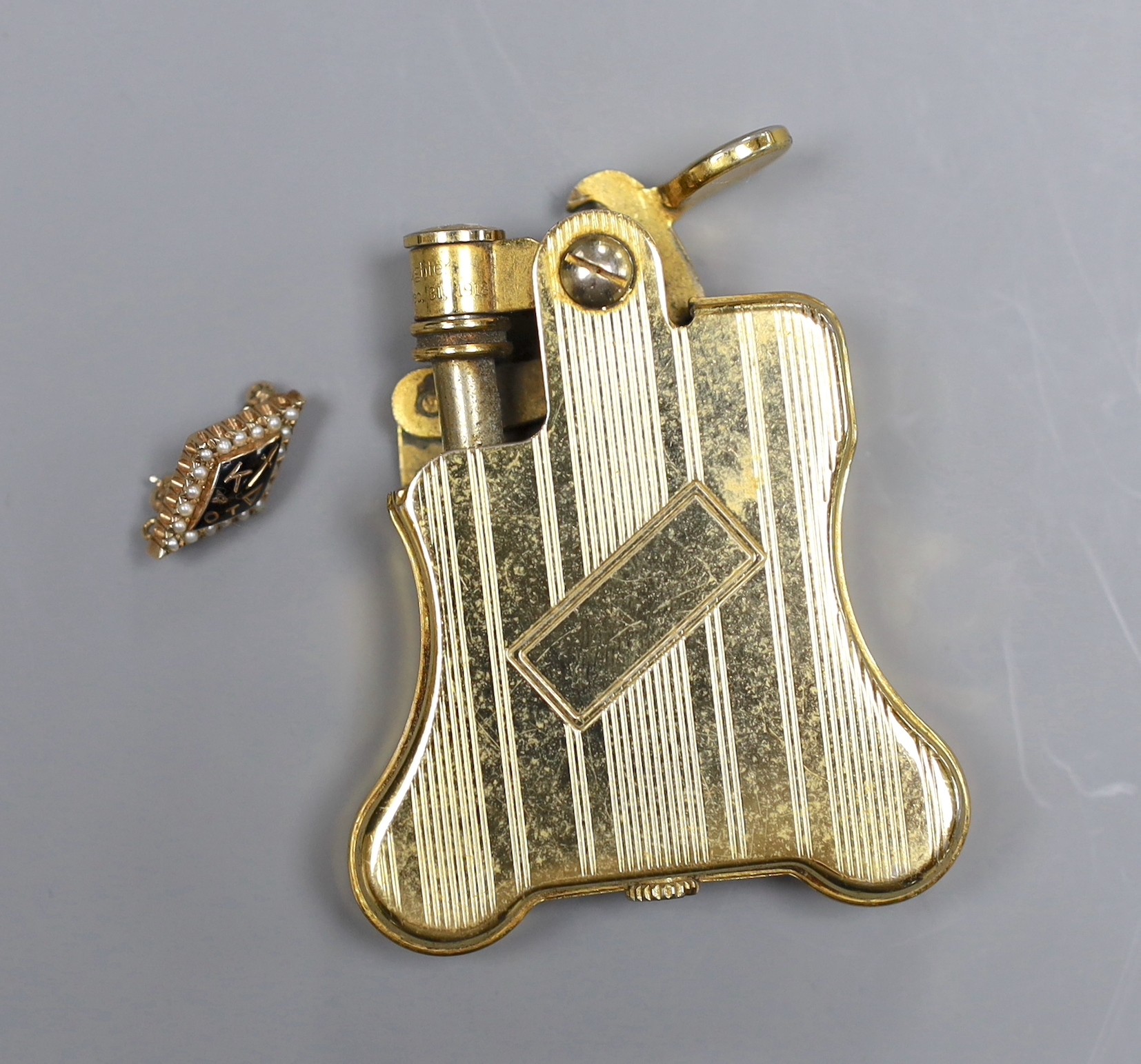 A Russian enamelled and seed pearl set brooch initialled KAOT, 1.75cm, gross 2.5 grams and a gold plated Ronson automatic cigarette lighter